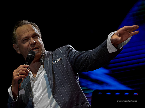 Retrato de Kurt Elling en plano medio cantando y haciendo un gesto con su brazo izquierdo hacia adelante y el cuerpo inclinado hacia atrás. En la composición se marca la diagonal correspondiente.