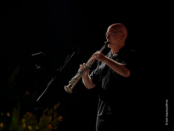 Dirk Descheemaeker de prfil tocando el saxo soprano. Se ven flores abajo a la derecha.