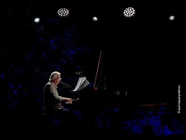 Retrato en plano general de Wim Mertens tocando el piano y cantando.