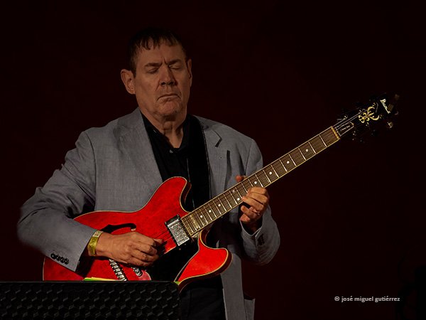 Chema Siaz toca en plano medio frontal su guitarra de intenso color rojo. Ojos cerrados, gesto serio.